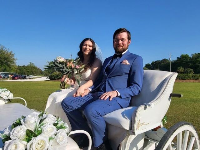 Nicole and Bryan seated together in a white horse-drawn carriage under a clear blue sky, bride holding a soft pink and white bouquet